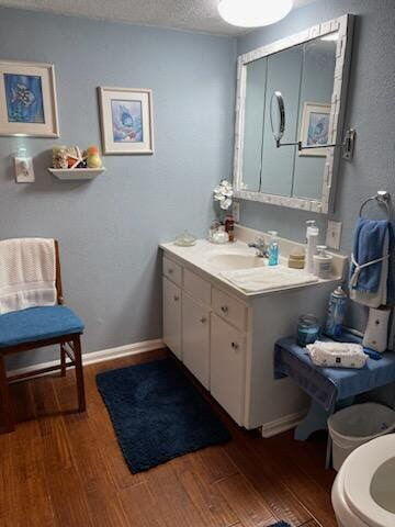 bathroom with baseboards, a textured ceiling, wood finished floors, and vanity