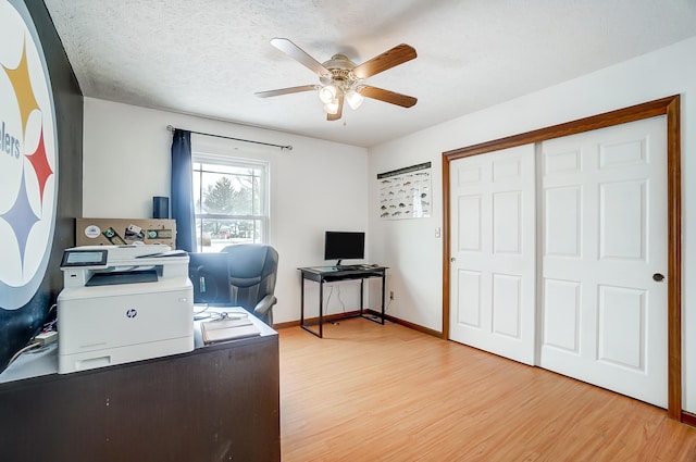 office featuring a ceiling fan, a textured ceiling, baseboards, and wood finished floors