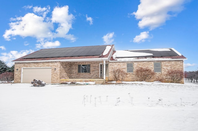 single story home featuring a garage, brick siding, and solar panels