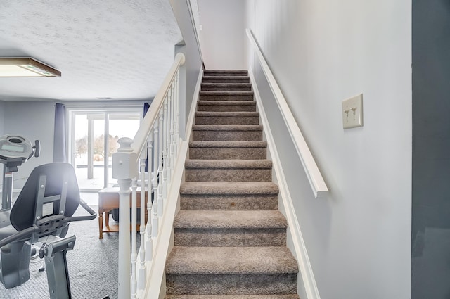 staircase with carpet flooring and a textured ceiling