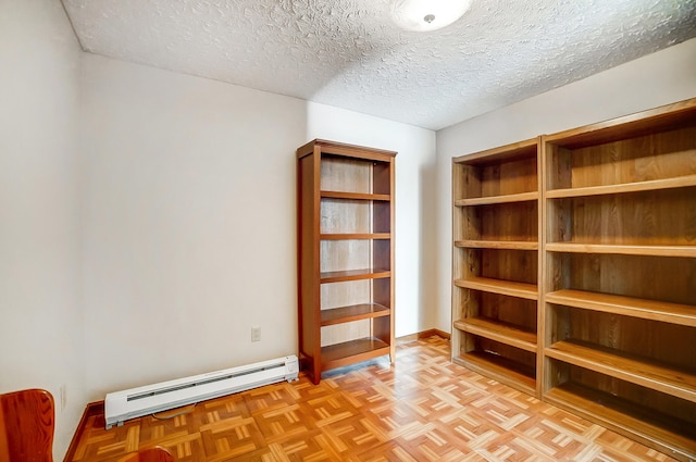 empty room with a textured ceiling, a baseboard radiator, and baseboards