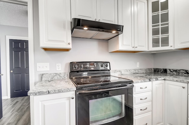 kitchen with white cabinets, black electric range oven, glass insert cabinets, and under cabinet range hood