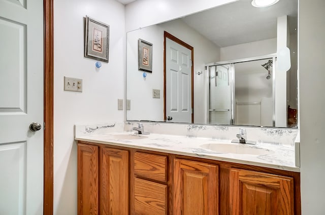 full bathroom with a shower with shower door, a sink, and double vanity