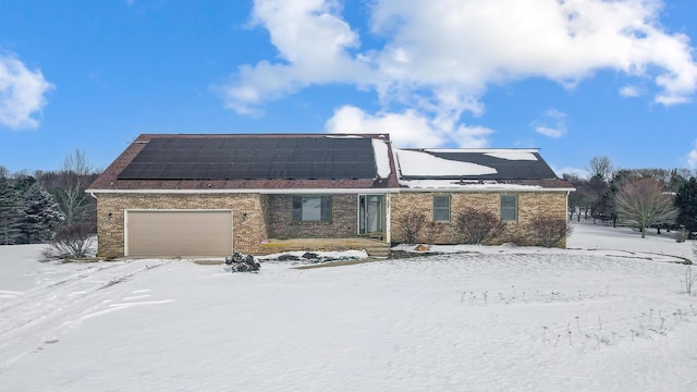 view of front of house featuring a garage, solar panels, and brick siding