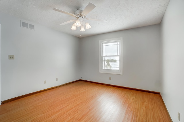 unfurnished room featuring baseboards, a textured ceiling, visible vents, and wood finished floors