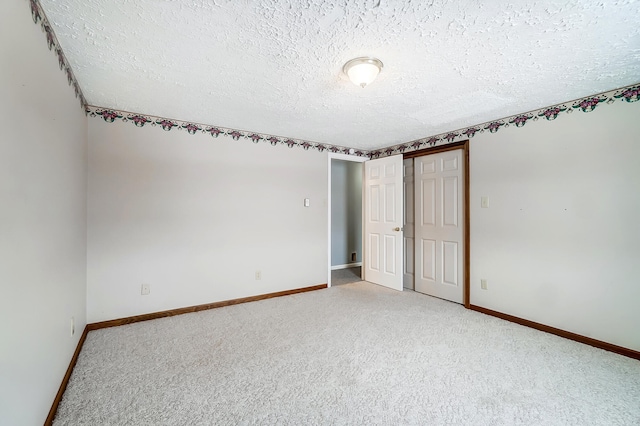 carpeted spare room featuring baseboards and a textured ceiling