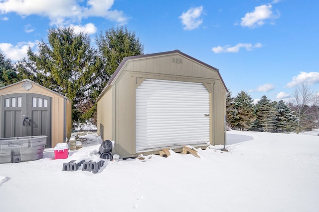 snow covered garage featuring a shed