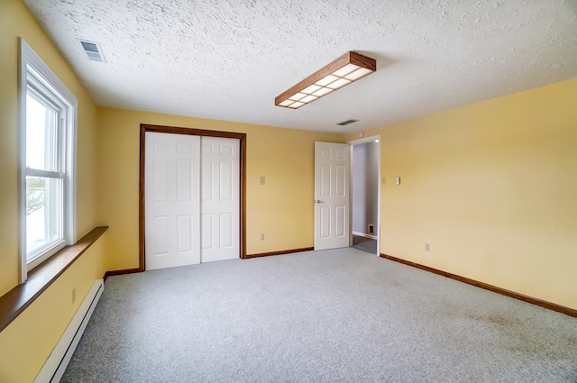 unfurnished bedroom featuring baseboards, visible vents, carpet floors, a baseboard heating unit, and a closet