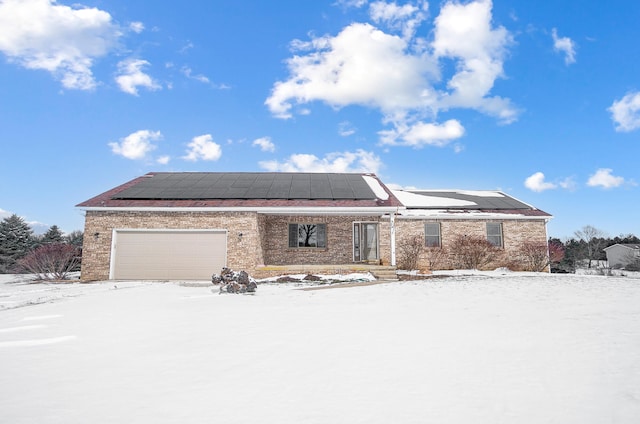 view of front of house with an attached garage, solar panels, and brick siding