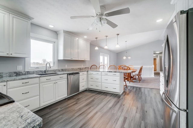 kitchen featuring white cabinets, decorative light fixtures, a peninsula, stainless steel appliances, and a sink