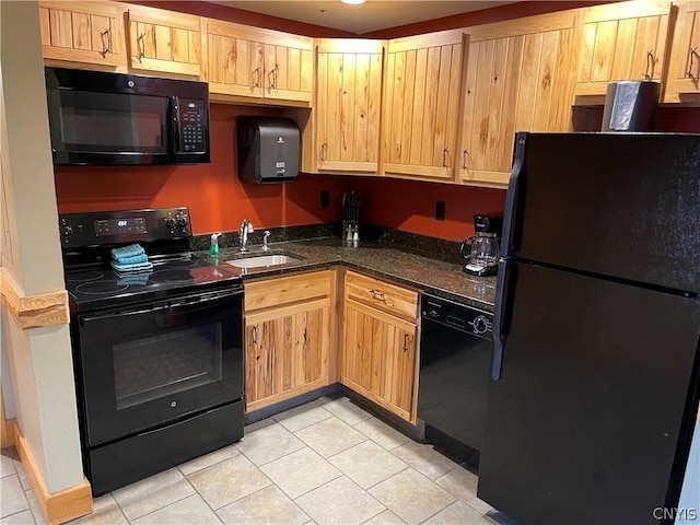 kitchen featuring light tile flooring, dark stone countertops, black appliances, and sink