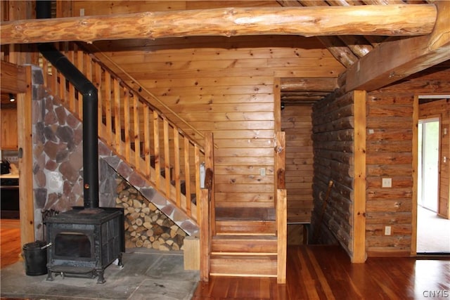 stairs featuring dark hardwood / wood-style flooring, a wood stove, beam ceiling, and rustic walls