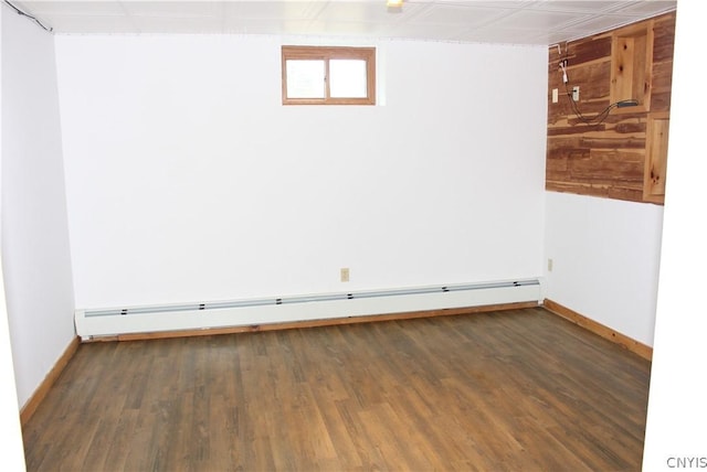 unfurnished room featuring a baseboard heating unit and dark hardwood / wood-style floors