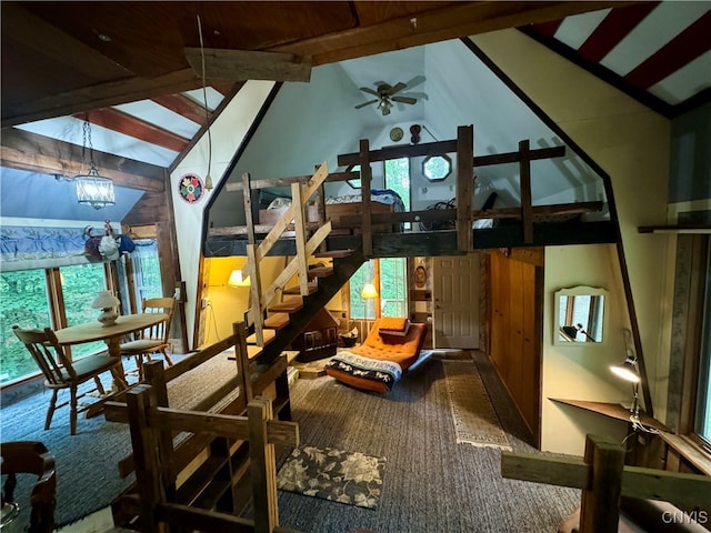 interior space featuring ceiling fan with notable chandelier, wooden walls, lofted ceiling, and carpet floors