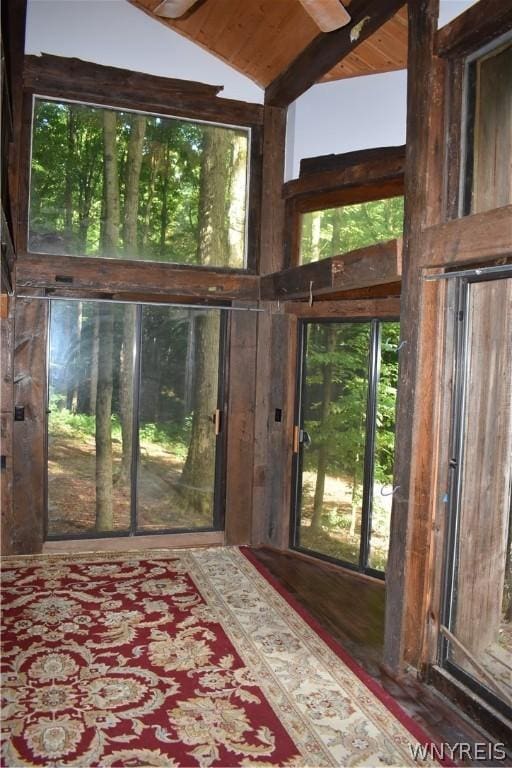 doorway to outside featuring dark hardwood / wood-style floors, plenty of natural light, vaulted ceiling with beams, and wood ceiling