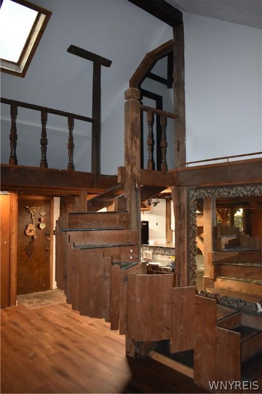 stairs with vaulted ceiling with skylight and wood-type flooring