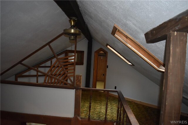 staircase featuring a textured ceiling and lofted ceiling with skylight