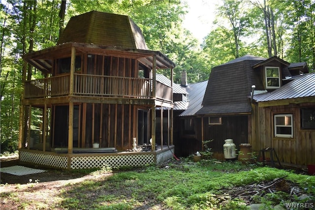 rear view of property featuring a balcony and a sunroom