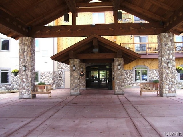 view of exterior entry with a balcony, a patio area, and french doors