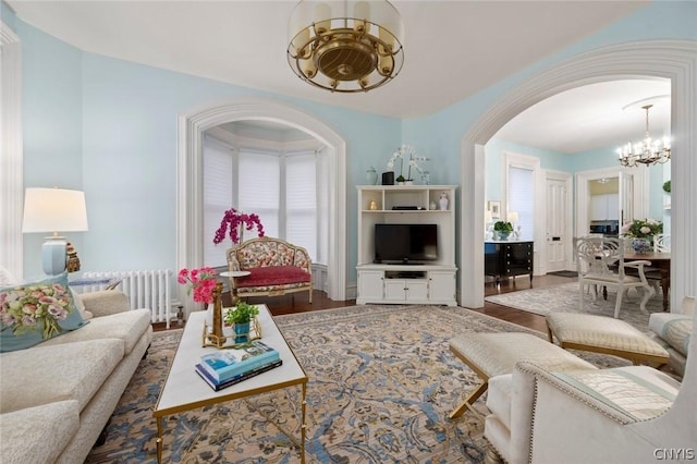 living room with radiator heating unit, dark wood-type flooring, and an inviting chandelier