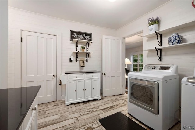 washroom featuring cabinets, ornamental molding, washing machine and dryer, and light wood-type flooring