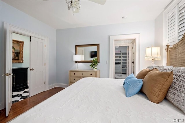 bedroom featuring a walk in closet, an inviting chandelier, a closet, and dark wood-type flooring