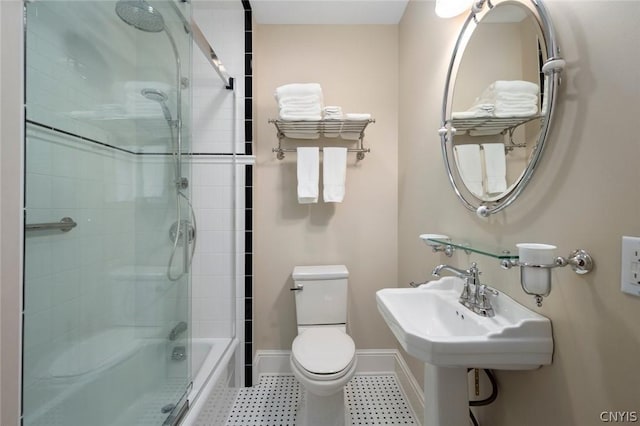 bathroom featuring toilet, shower / bath combination with glass door, and tile flooring