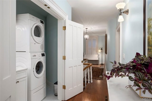 clothes washing area with tile floors and stacked washer / drying machine