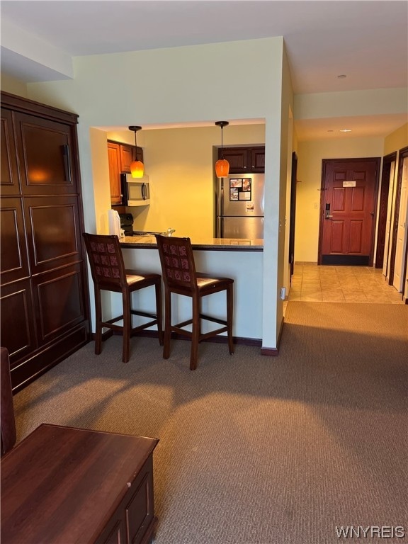 kitchen featuring light carpet, decorative light fixtures, and stainless steel appliances