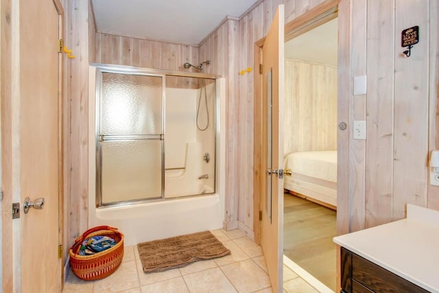 bathroom with vanity, shower / bath combination with glass door, tile flooring, and wood walls