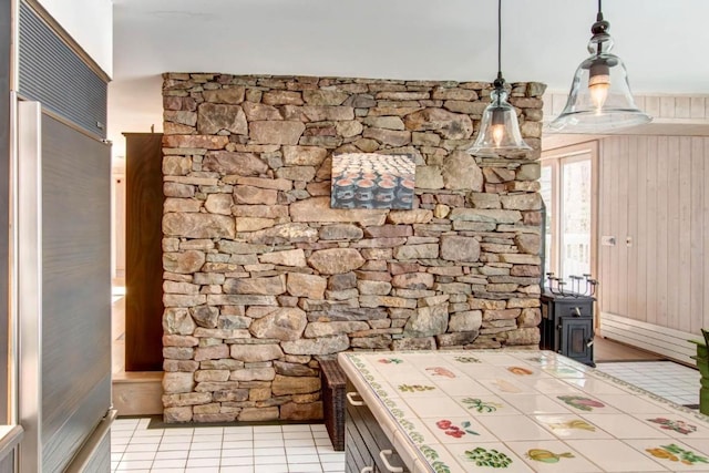 interior space with hanging light fixtures, tile countertops, and light tile floors