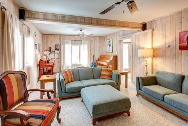 carpeted living room featuring ceiling fan and wood walls