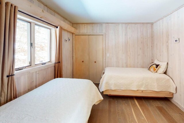 bedroom with wood walls, a closet, and wood-type flooring