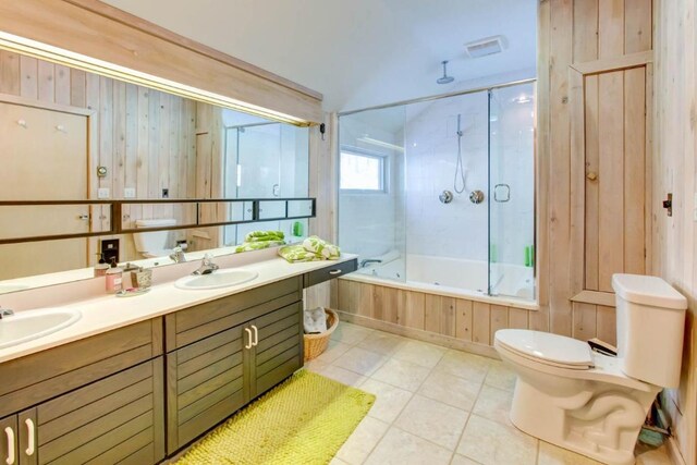 full bathroom featuring wood walls, tile flooring, toilet, double vanity, and enclosed tub / shower combo