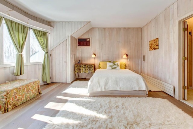 bedroom with wooden walls and light hardwood / wood-style flooring