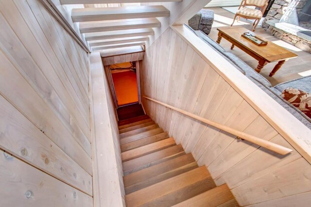 stairway with beam ceiling and wood walls