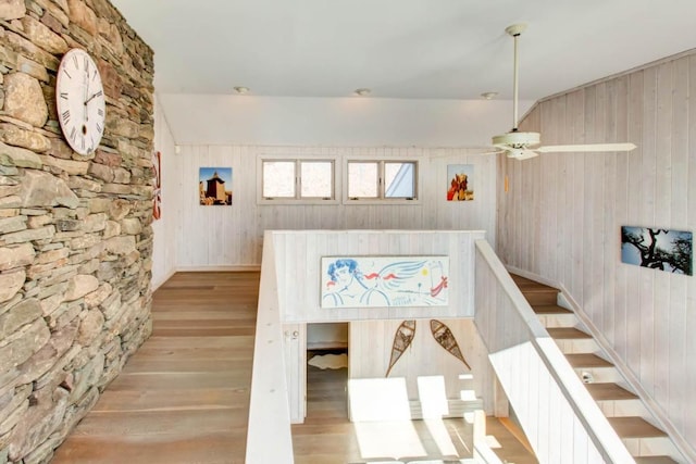 interior space featuring wood walls, ceiling fan, and light wood-type flooring