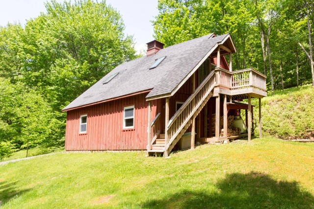 back of property with a wooden deck and a lawn