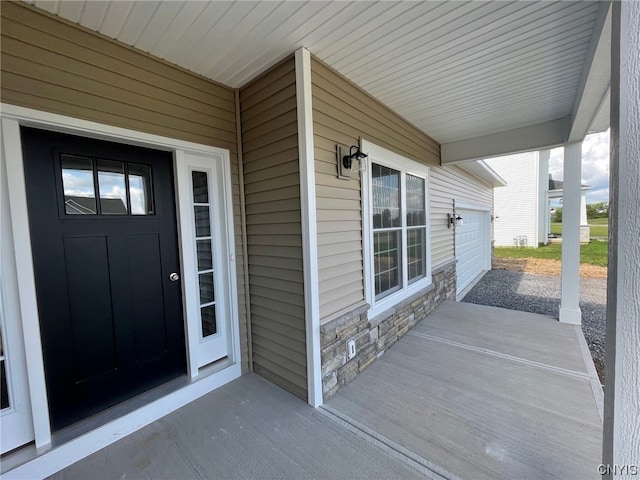 doorway to property with covered porch and a garage