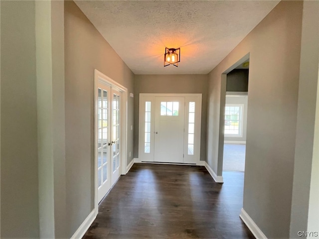 entrance foyer with dark wood-type flooring, a textured ceiling, and french doors