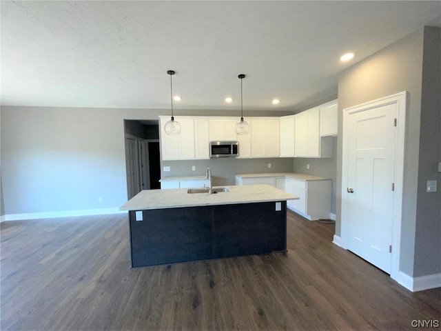 kitchen with a center island with sink, decorative light fixtures, and dark wood-type flooring