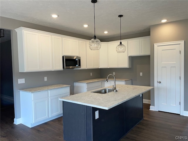 kitchen with dark hardwood / wood-style flooring, white cabinetry, a center island with sink, pendant lighting, and sink