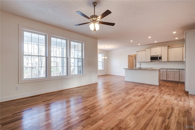 unfurnished living room with ceiling fan, light hardwood / wood-style flooring, and sink