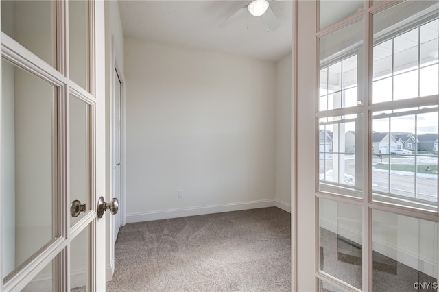 carpeted spare room featuring plenty of natural light and ceiling fan