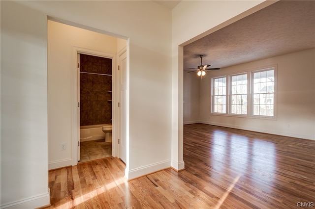 spare room with light hardwood / wood-style floors, ceiling fan, and a textured ceiling