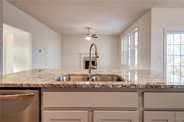 kitchen featuring plenty of natural light, stainless steel dishwasher, ceiling fan, and sink