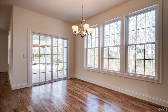 empty room featuring dark wood-type flooring and a chandelier