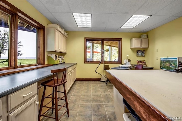 1567 Lake Rd, Porter, NY 14174 - kitchen with a paneled ceiling, a breakfast bar, and light tile floors
