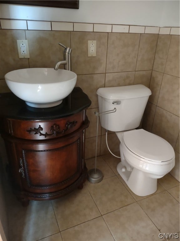 bathroom featuring tile walls, tile flooring, toilet, and vanity