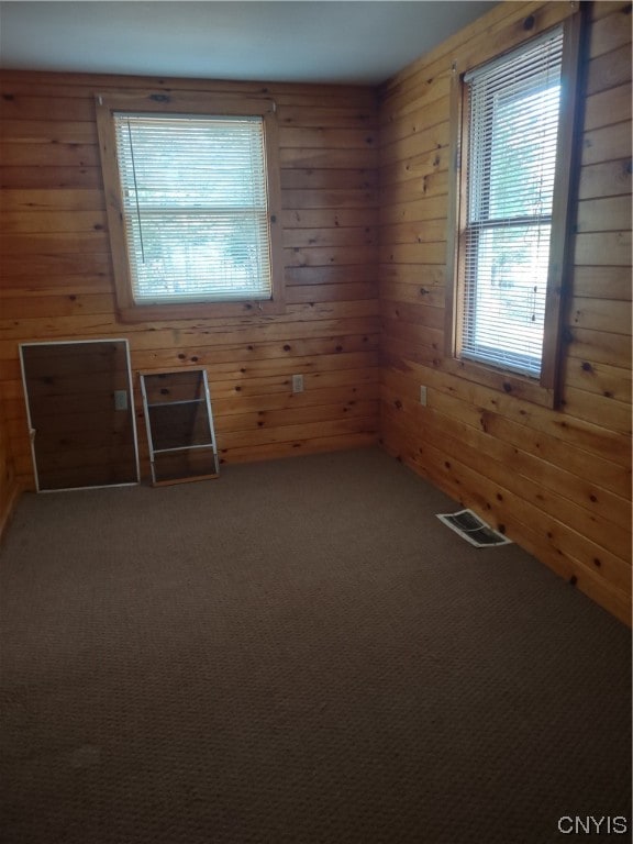 carpeted spare room featuring wood walls